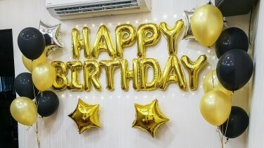 21st birthday balloon decor event image with black and gold balloons and foil balloons that spell out happy birthday