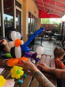 Person holding out a penguin with a blue fishing pole all made out of balloons.