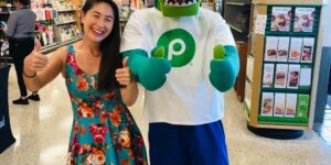 woman in green dress with alligator mascot at publix brand store promo event