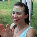 A happy client claps and wears face paint at a birthday party