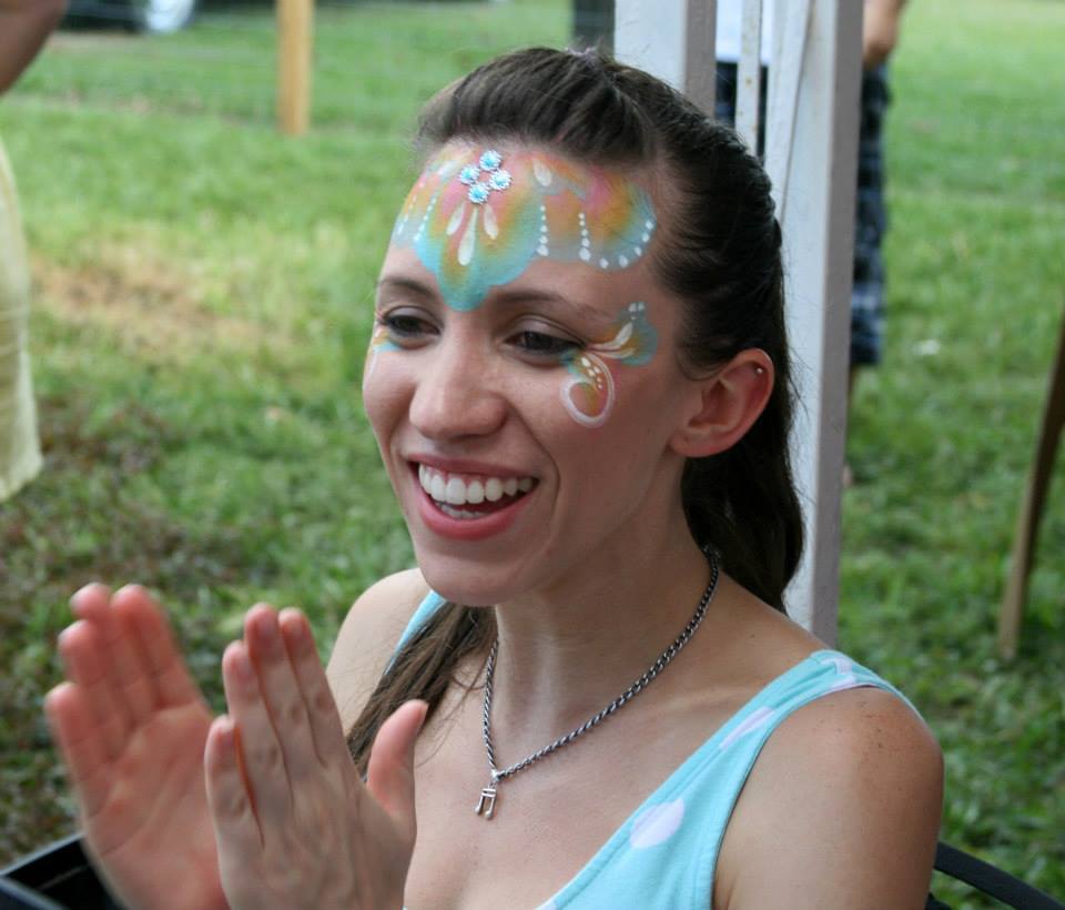 A happy client claps and wears face paint at a birthday party