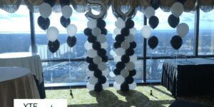 A pair of black and white balloon columns with foil balloon toppers displaying the number fifty.