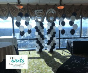 A pair of black and white balloon columns with matching organic balloon decor.
