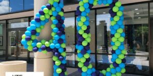 A pair of blue navy and green balloon sculptures creating the number forty outside of the entrance to the FrankCrum business offices.
