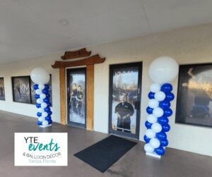 A pair of white and blue balloon columns, one of each side of the entrance to a martial arts school.