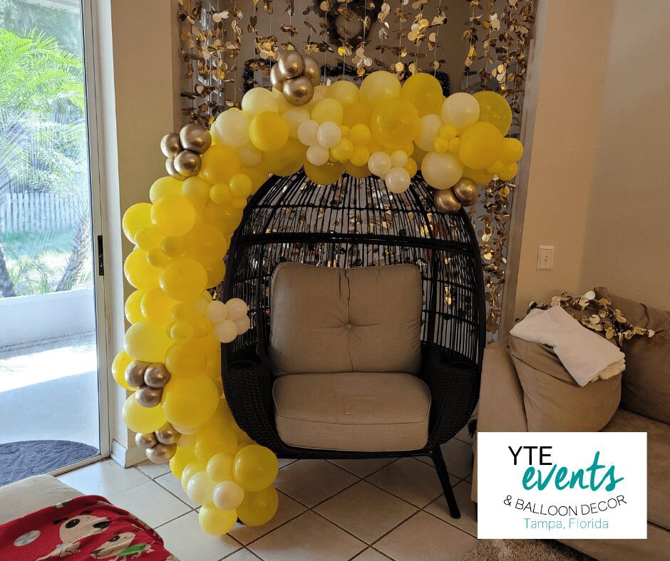 Baby shower balloon decor for private residence made with yellow and gold balloons in a crescent shape.