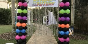 Back to the future themed entrance with silver tassels and neon columns of balloons