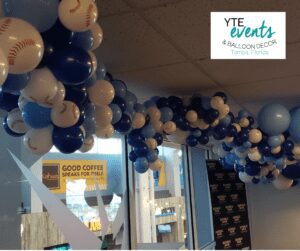 Blue and white balloon ceiling decor where the white balloons are baseball-patterned.
