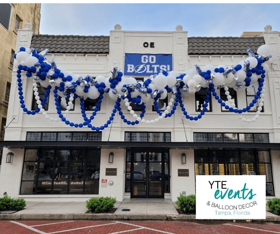 Blue and white organic balloon decor hung above the awning of the Oxford Exchange with strings of blue and white balloons hanging down from the main decor piece.