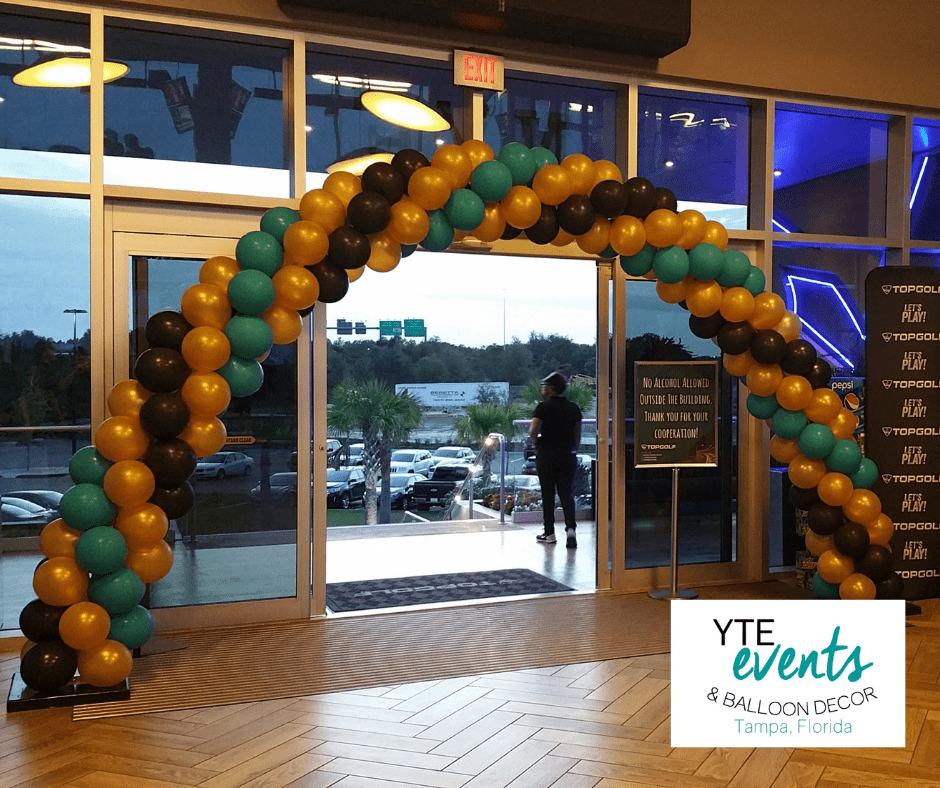 Green yellow and black balloon archway for the entrance to the TopGolf lobby.