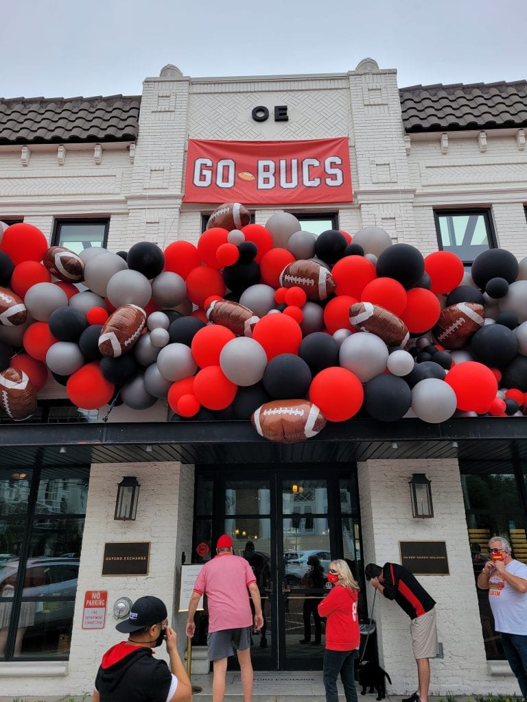 People are excited about the game and are taking photos with the balloon decorations at oxford exchange in tampa on kennedy scaled