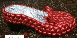 Red foil balloon sculpture made to look like a slipper with a silver foil lining on the inside.
