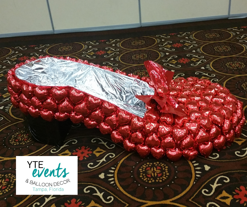 Red foil balloon sculpture made to look like a slipper with a silver foil lining on the inside.