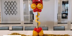 Short orange and red balloon column topped with a red star foil balloon for a table centerpiece