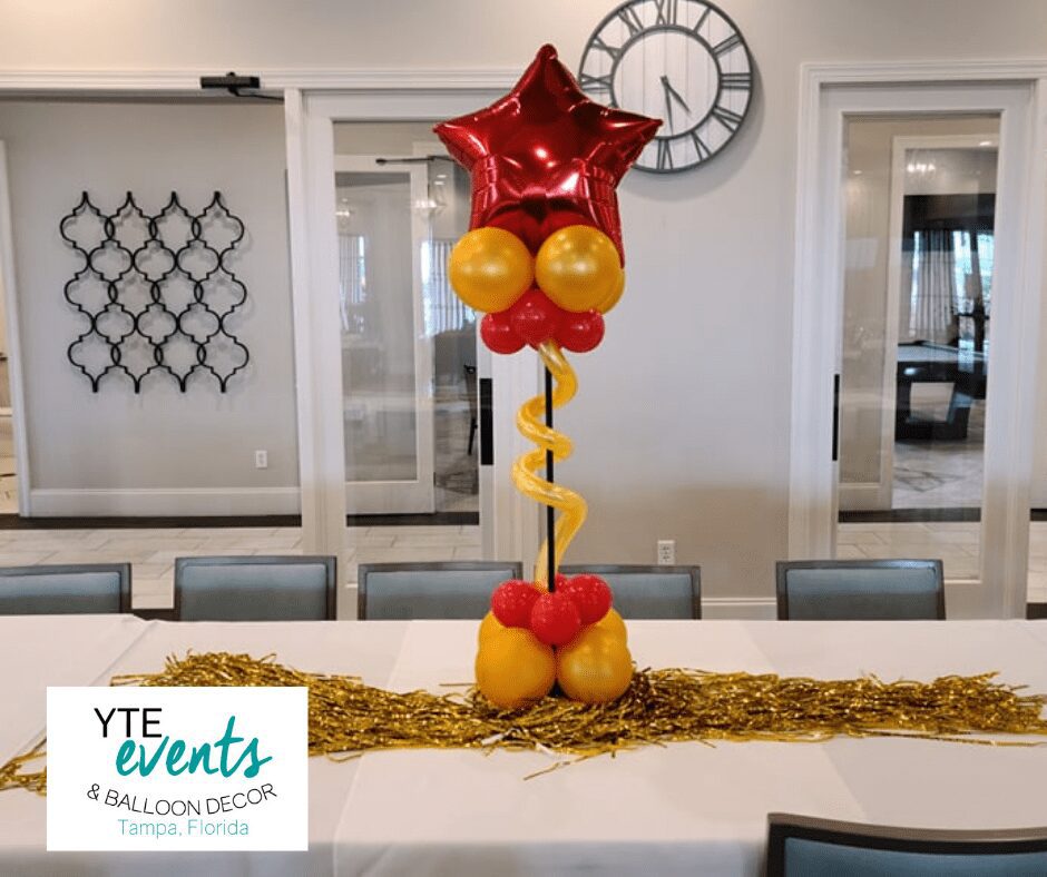 Short orange and red balloon column topped with a red star foil balloon for a table centerpiece