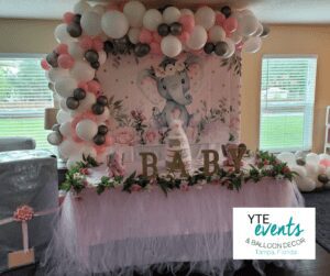 White and pink balloon ceiling decor above a pink lace-topped table and a cartoon elephant curtain.