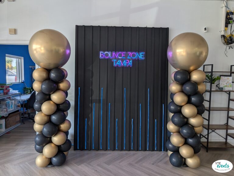 Tall black and gold balloon columns with large gold balloons on top at Bounce Zone Tampa corporate event