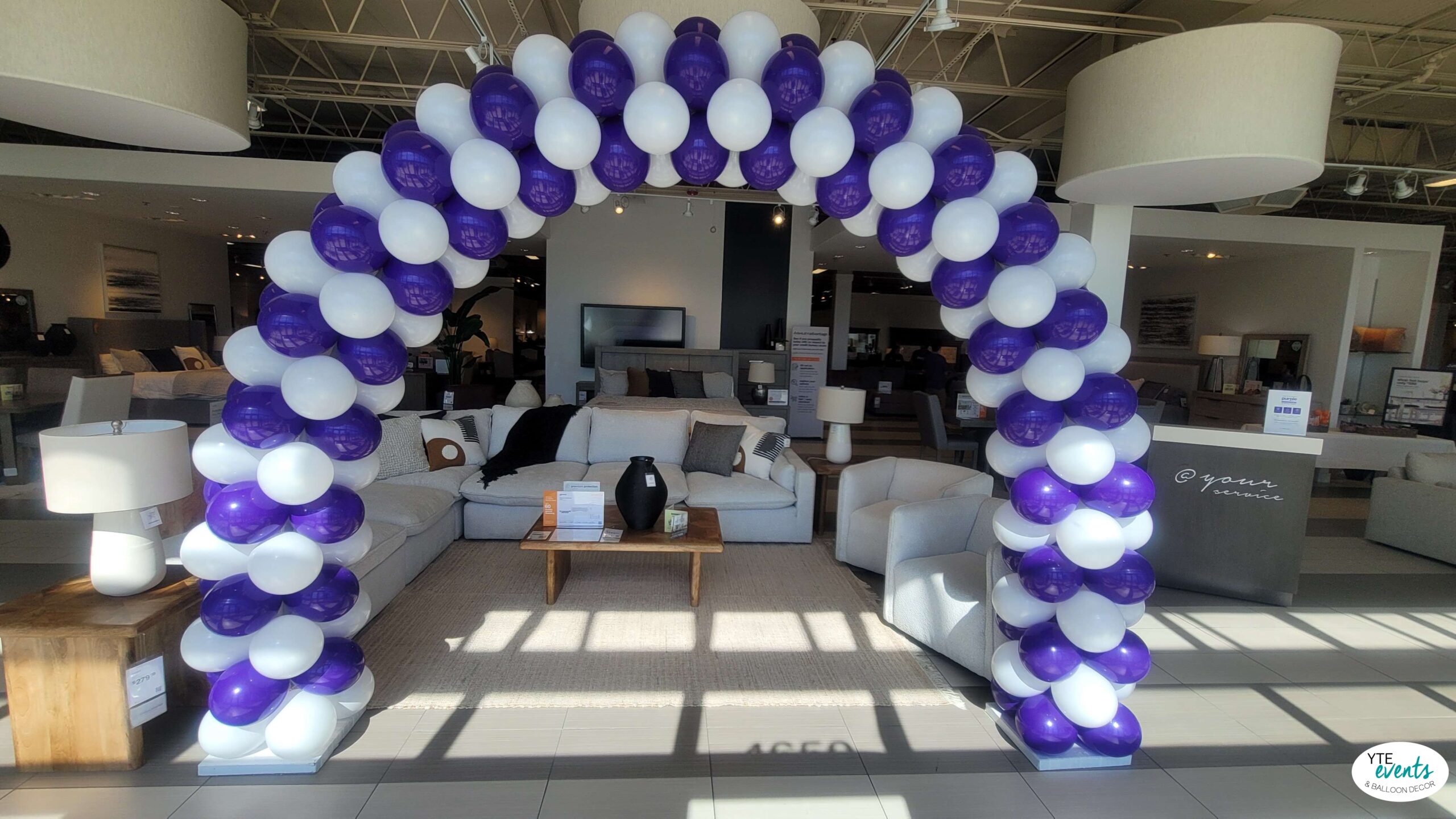 Blue and white balloon arch in a modern furniture showroom for corporate event styling