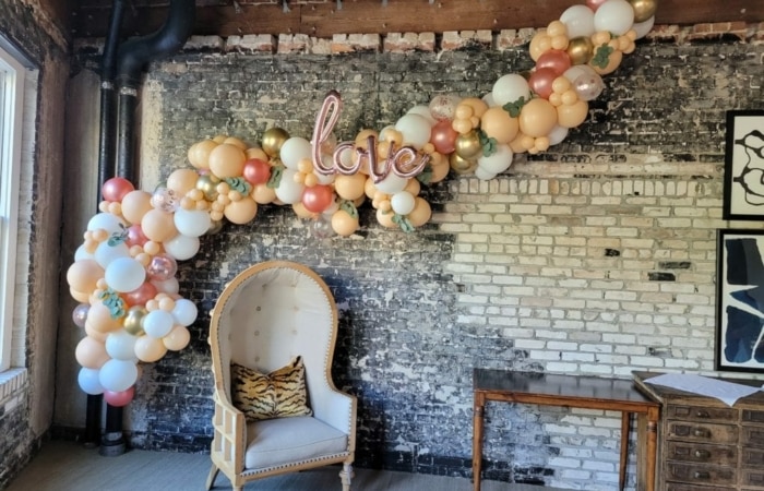 air filled balloon decor organic garland on wall over chair for baby shower in pinks and blush colors for Air Filled Balloon Decor vs. Helium discussion