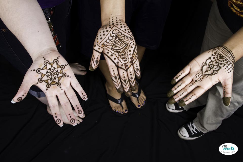 Three hands decorated with intricate Mendhi henna designs at a bridal shower in Tampa