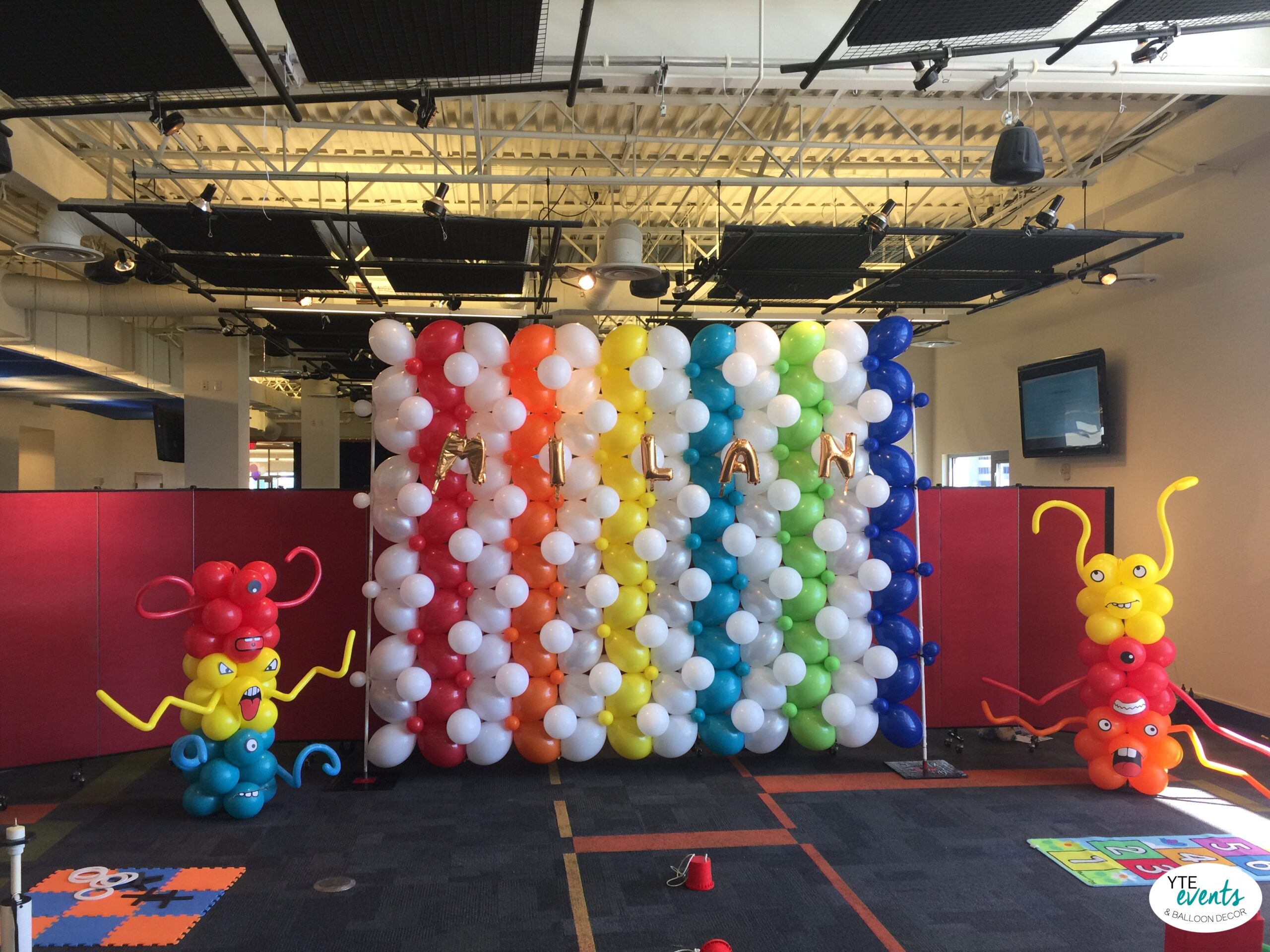 Colorful monster-themed balloon wall with bold rainbow stripes and playful balloon monsters for a kid's birthday event