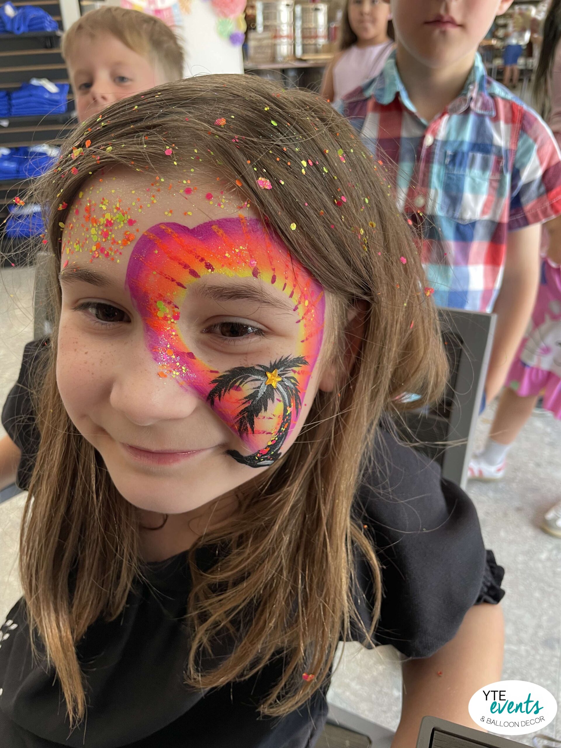 Young girl with bright heart-shaped neon face paint and glitter at a kids birthday party