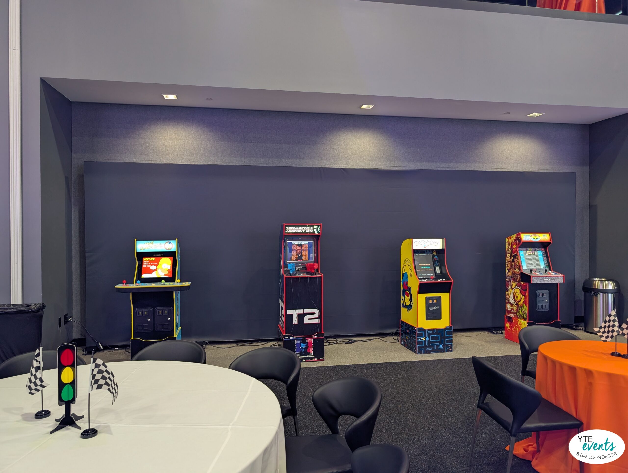 Arcade game machines lined up with themed table decor in a modern event space