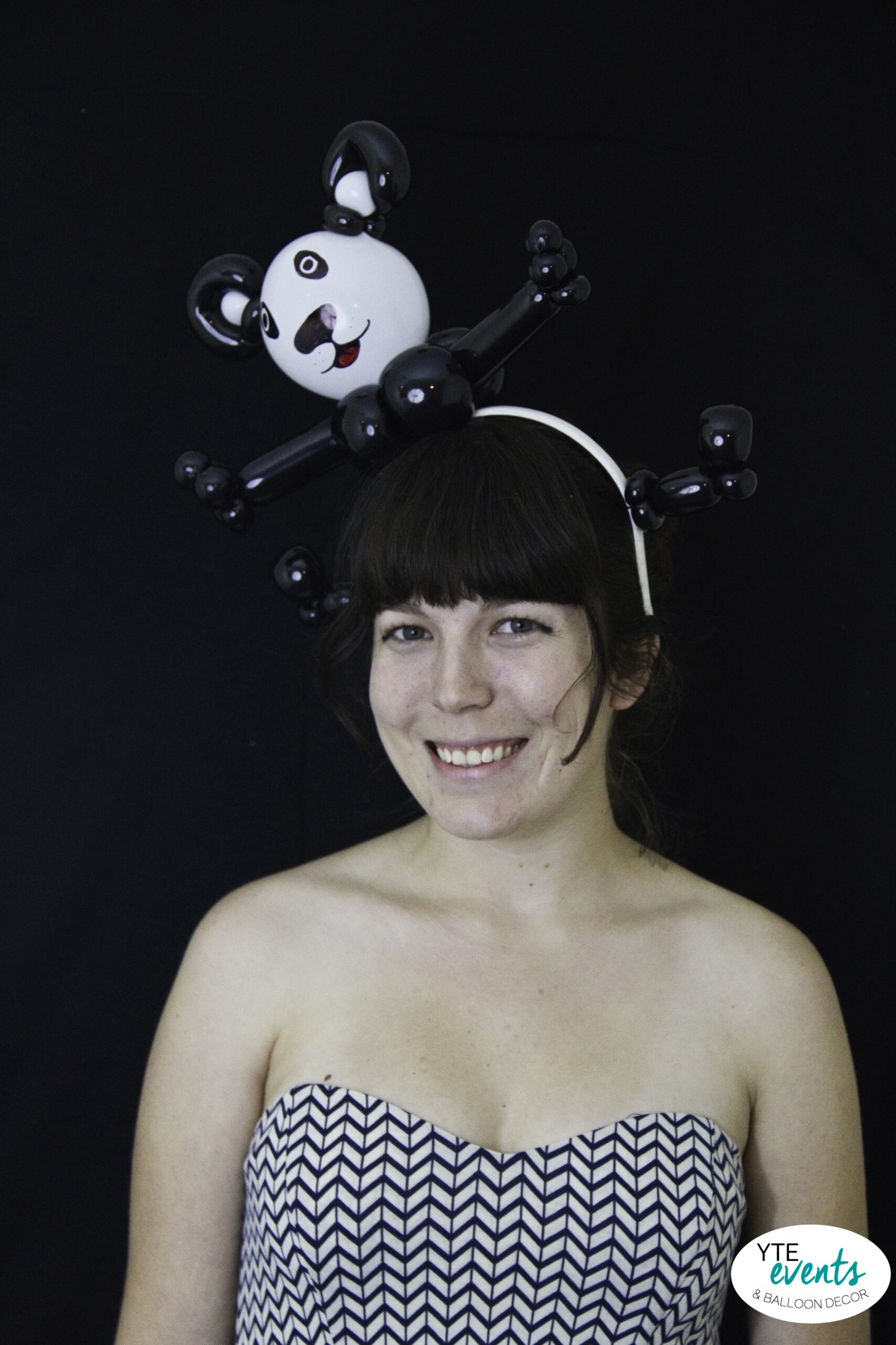 Woman wearing a black and white custom balloon panda headband on a black background