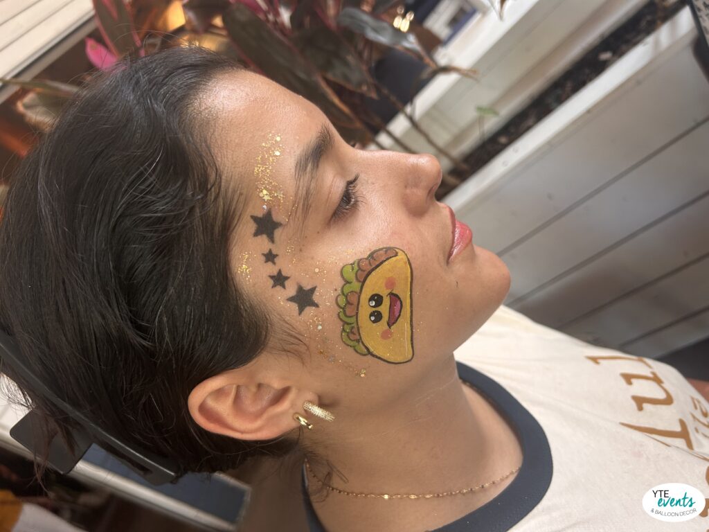 Young woman with cute taco face painting and black stars on cheek at a festival
