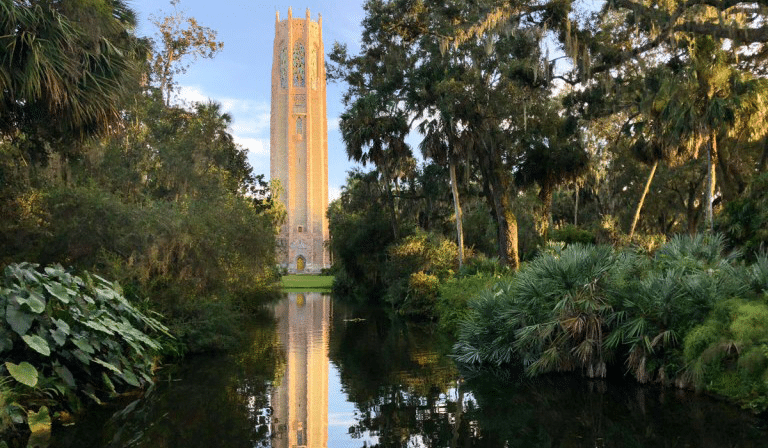 The iconic 205-foot Singing Tower, winding paths lined with flowers and lush greenery, secret hideaways, Mediterranean estate, and the cute on-site café combine to make Bok Tower Gardens the perfect destination for a date day trip. This is a photo of that tower amidst the florals and the lake.