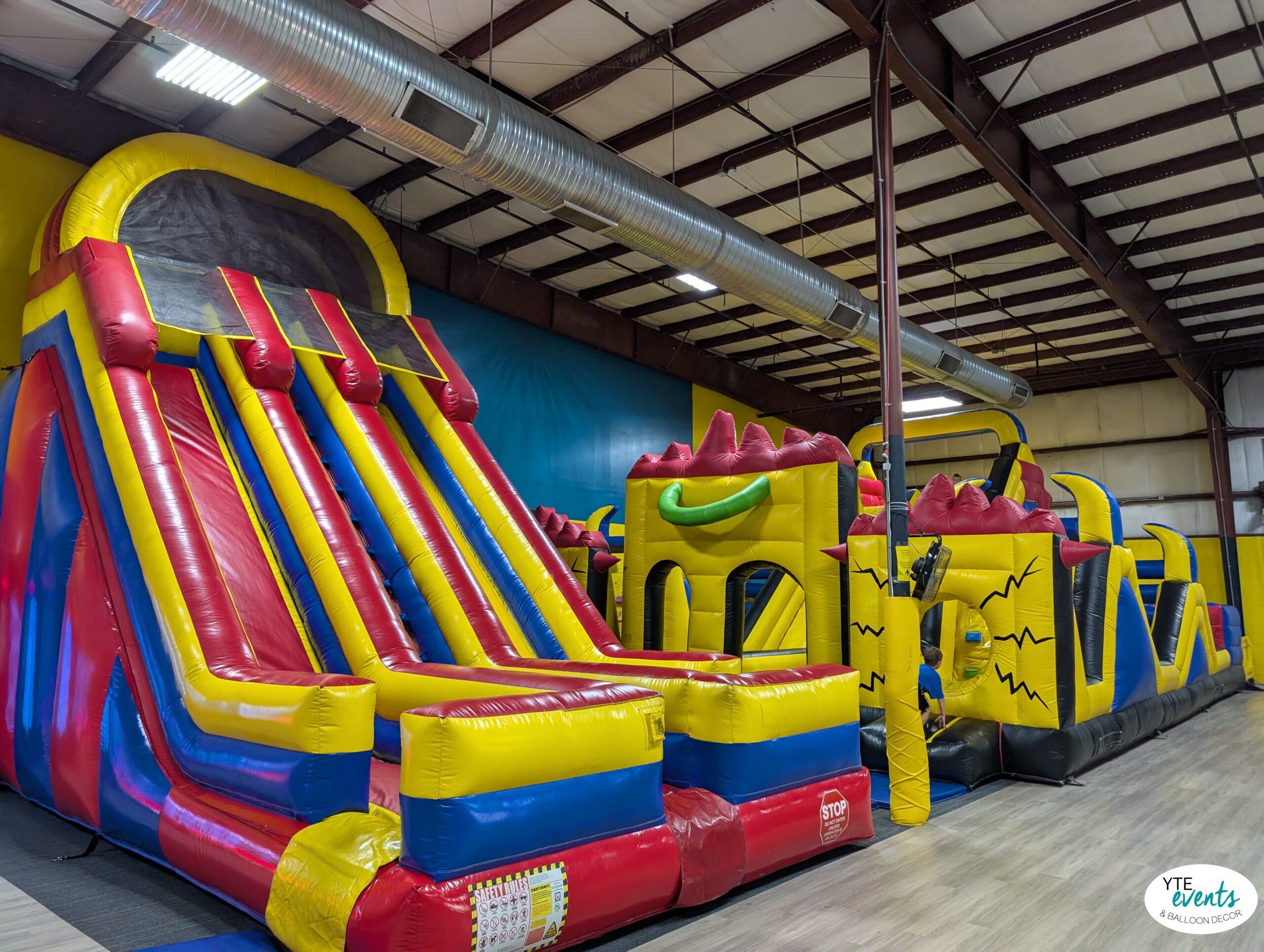 Large colorful inflatable bounce house and slide in an indoor play area with red, yellow, blue colors