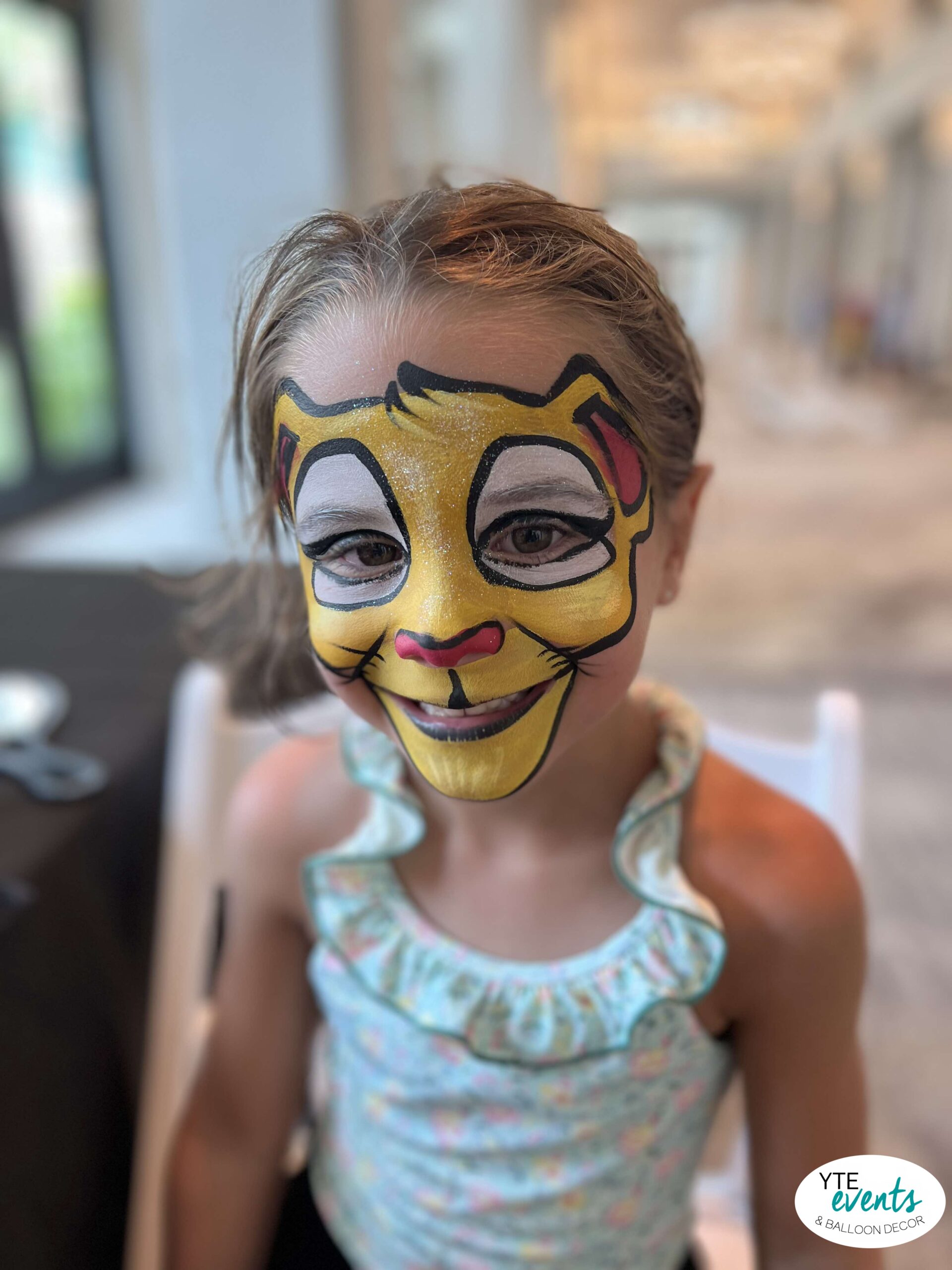 Child with vibrant yellow lion face painting at a kids party event