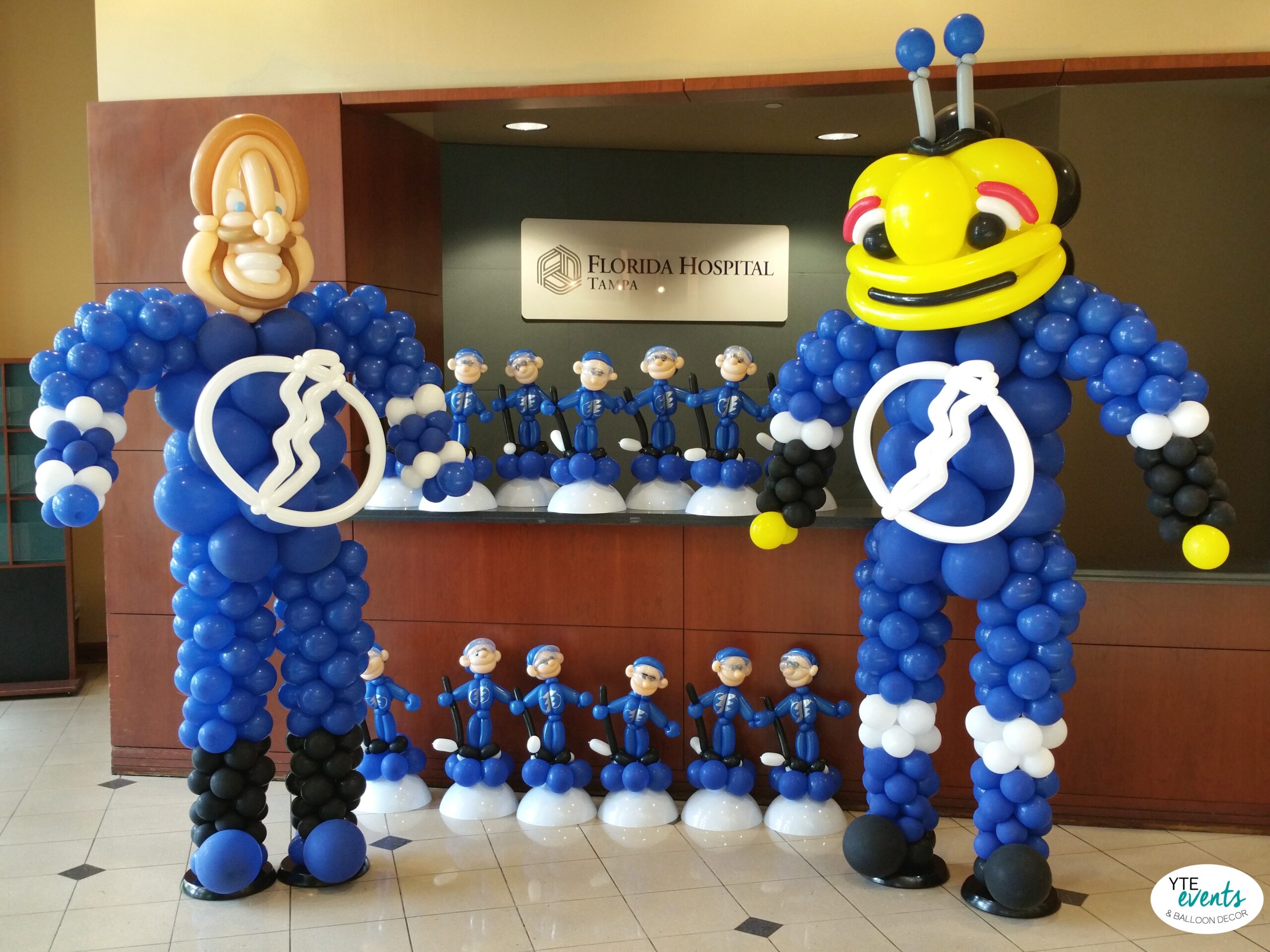 Large blue and white balloon mascot sculptures and smaller matching balloon figures arranged in front of Florida Hospital Tampa sign