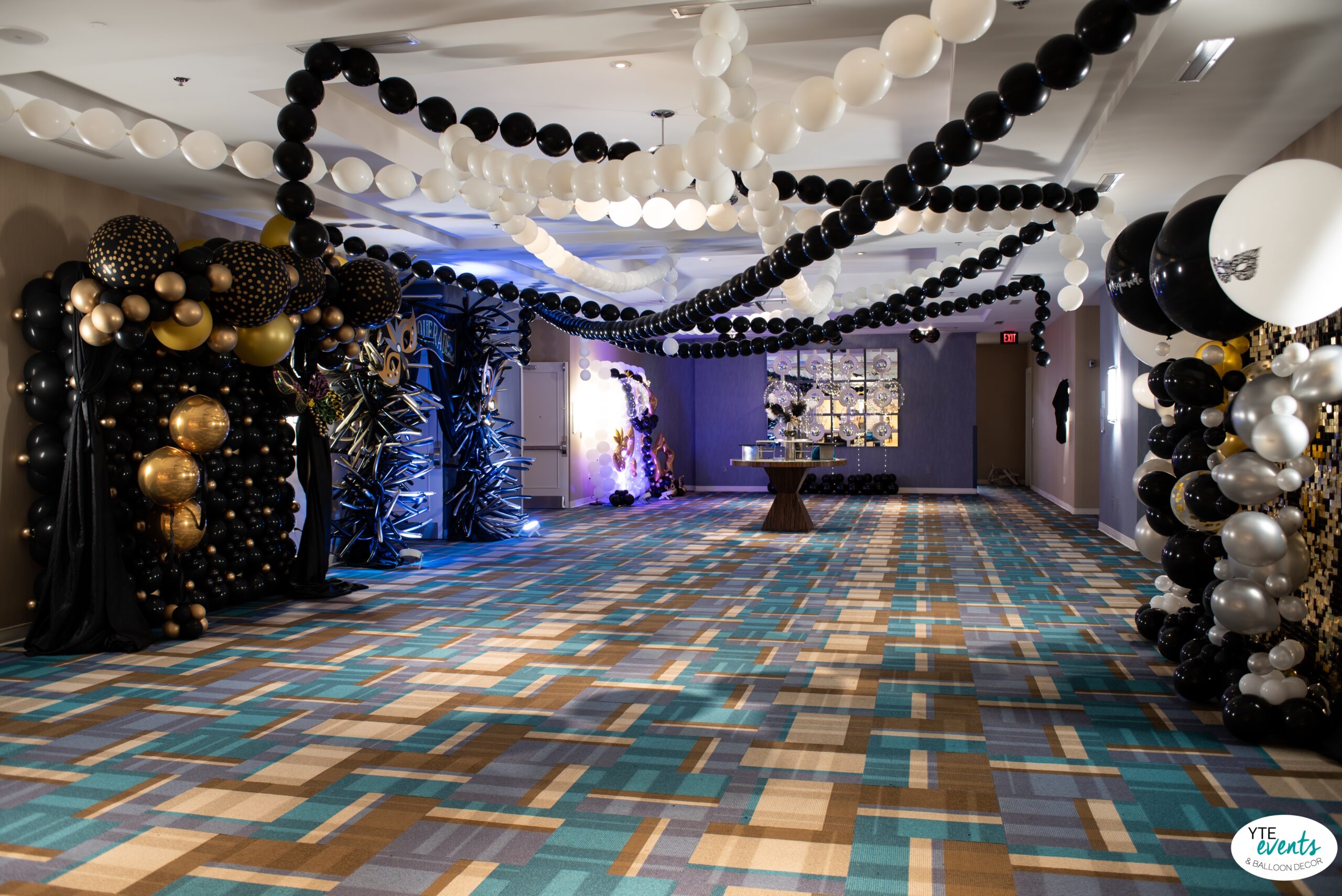 Luxurious black, white, and gold balloon decor and garlands at masquerade ball event venue