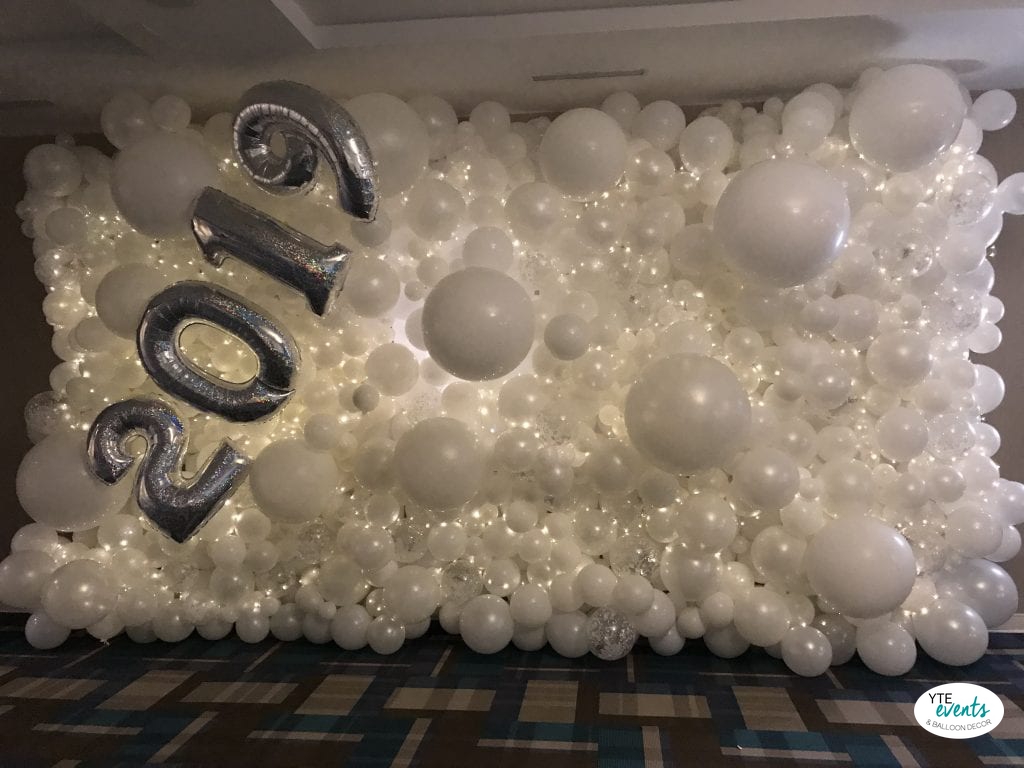 Large white balloon wall with twinkling lights and silver 2021 foil balloons for New Year celebration
