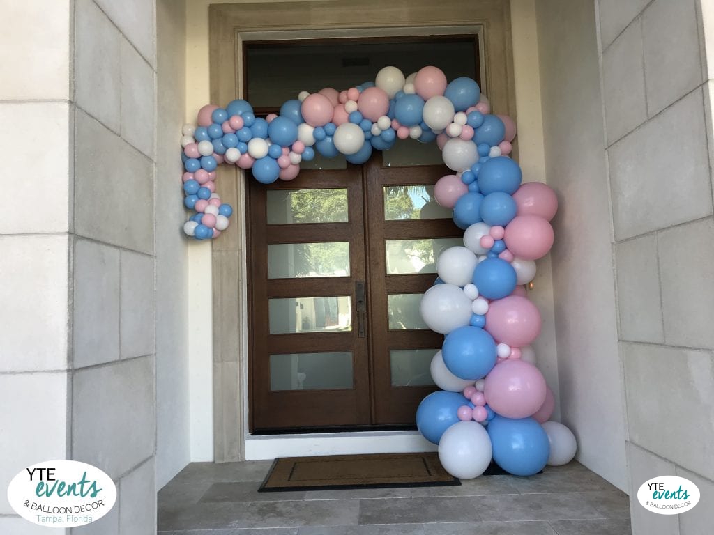 Organic balloon demi-arch in blue, pink, and white decorating an entrance for a baby shower