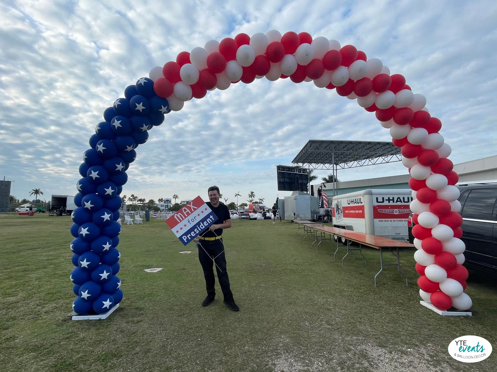 Red, white, and blue patriotic balloon arch with stars at an outdoor political campaign event