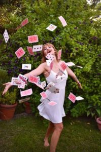 shelbi magician throwing playing cards in front of a hedge