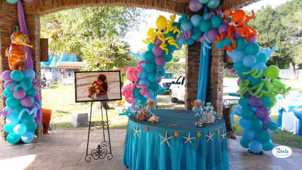 Under the sea themed balloon arch with colorful octopus balloons and blue table with starfish decor