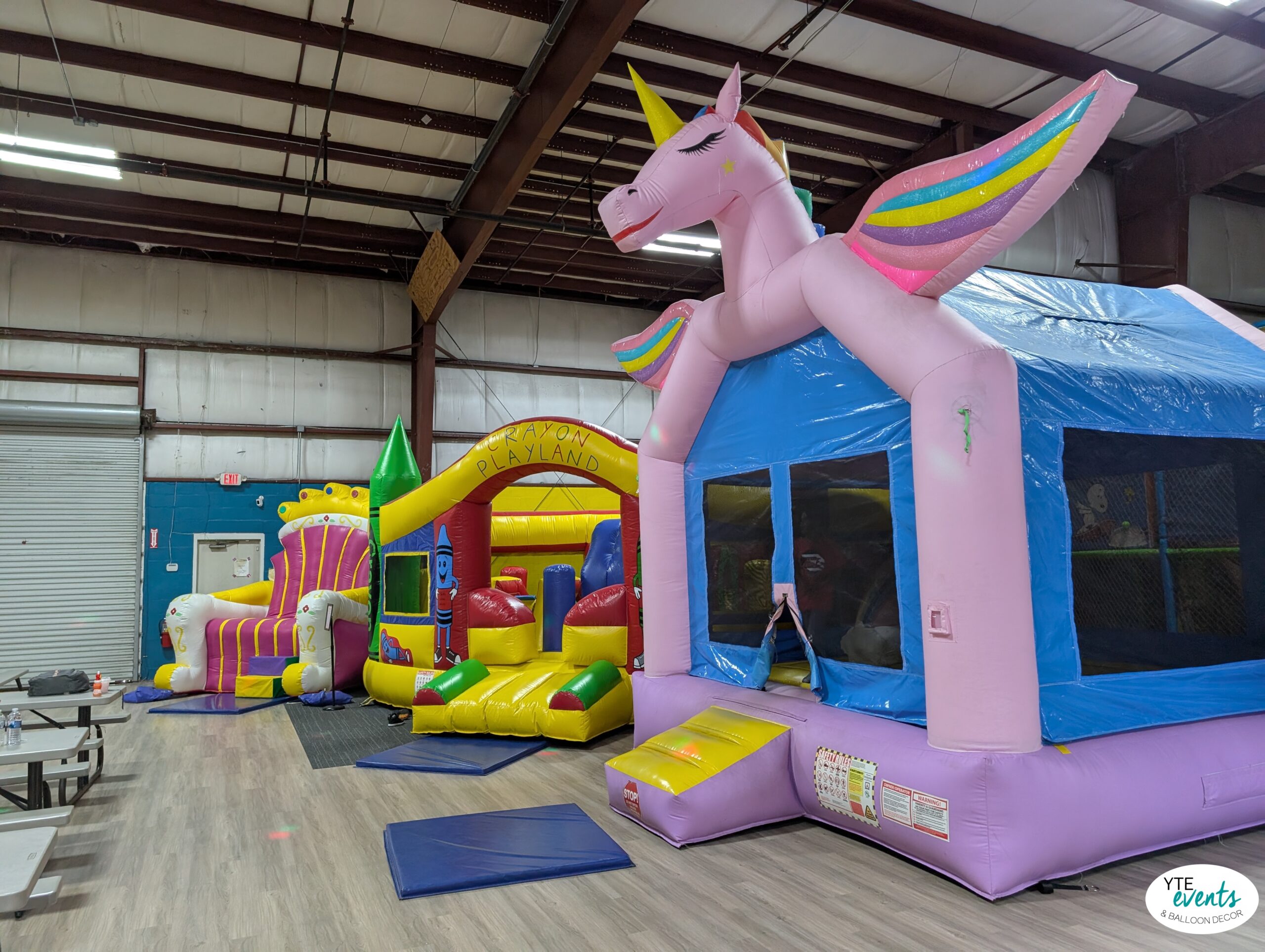 Indoor inflatable playland with unicorn-themed bounce house and colorful party balloons