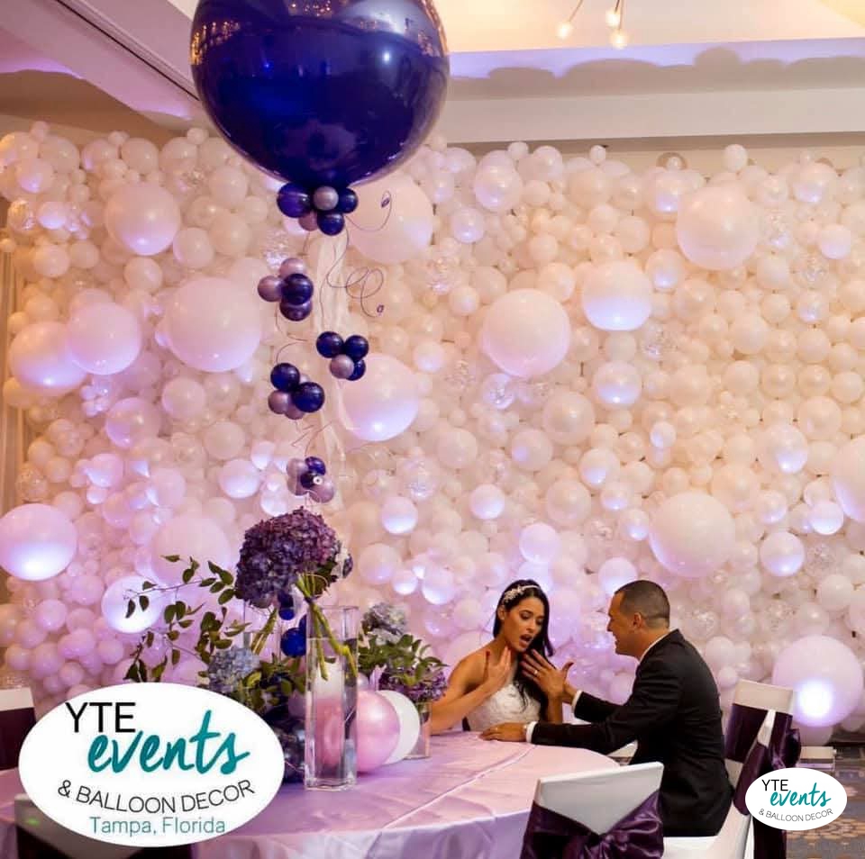 Elegant white balloon wall backdrop with a large blue balloon centerpiece at a wedding reception