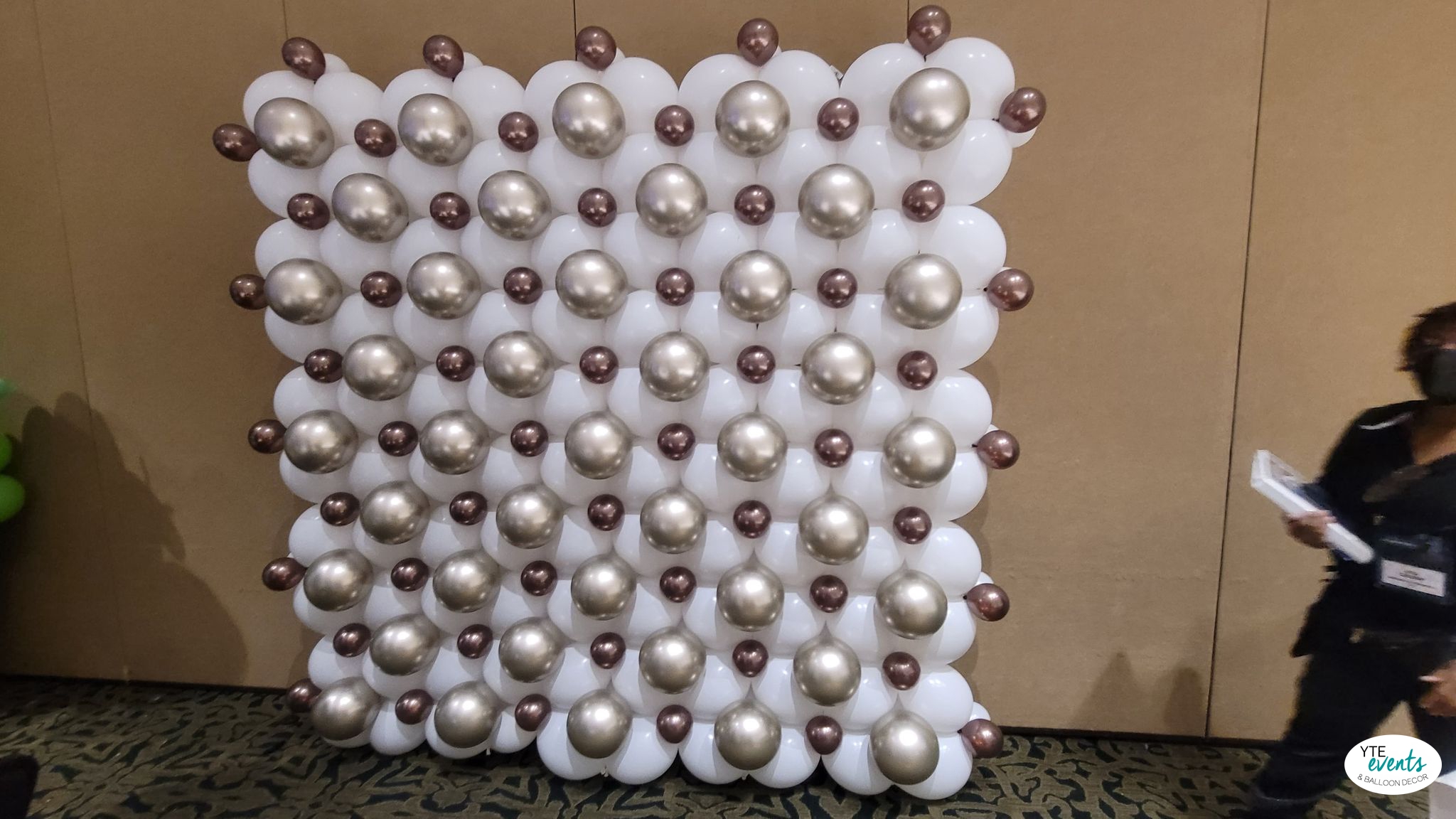 White balloon wall decorated with metallic silver and bronze dots creating a stylish event backdrop